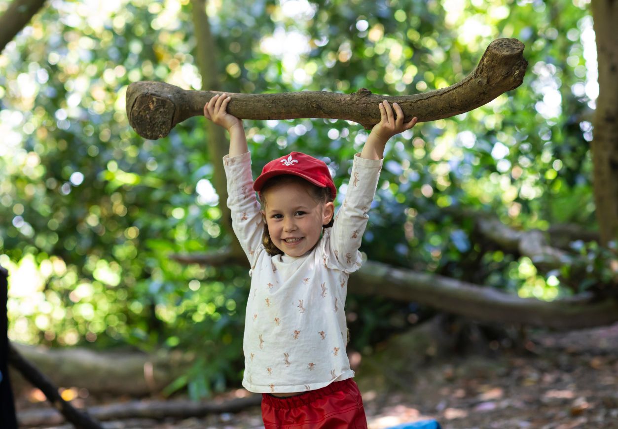 pre-prep child holds up branch in woods