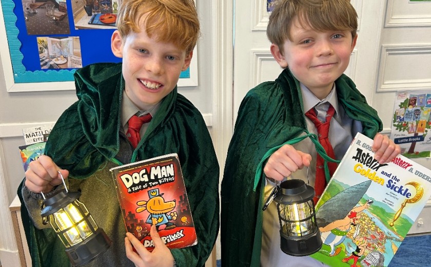 two smiling children holding lamps and books