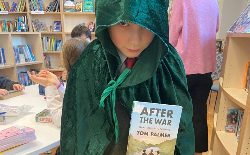 boy dresses up in a dark cloak holding a book