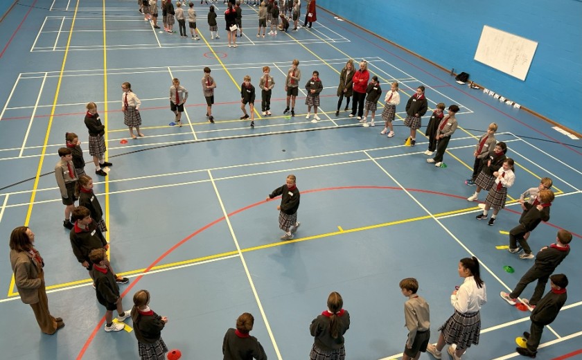 year 5 and 6 pupils gathered in circles playing games in the sports hall