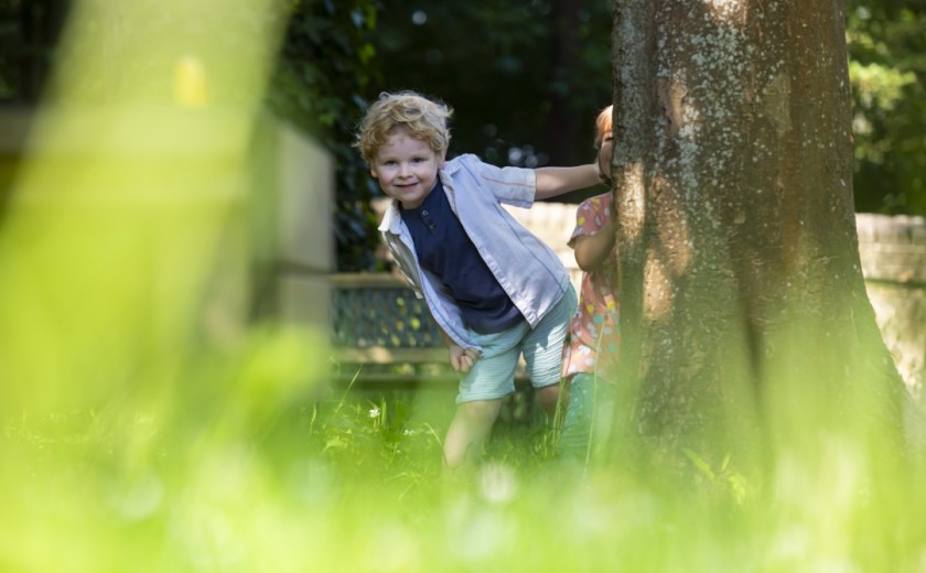 boy in the secret garden playing boo behind a tree