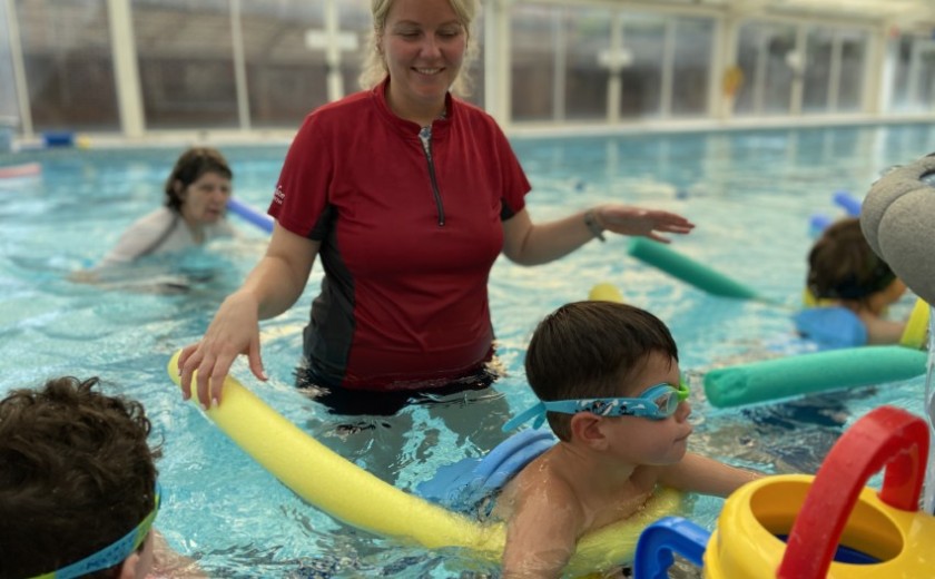 little children with pool noodles swimming 