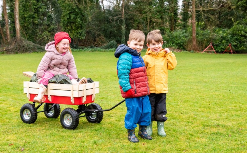 children pull a trolley to forest school