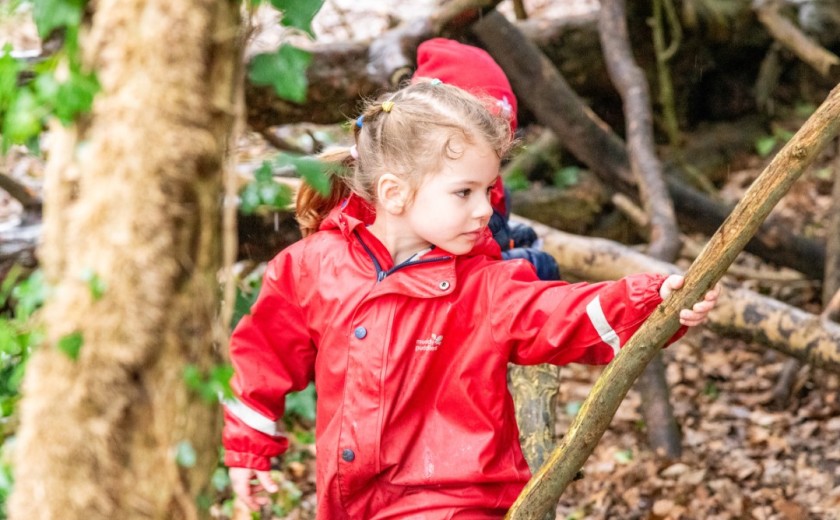child in red onesie in woods