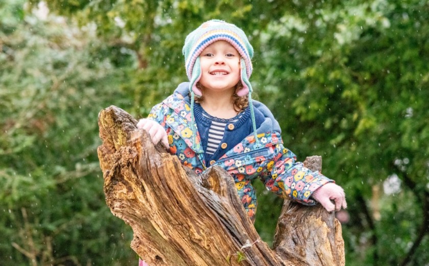 girl in woods climbs onto log