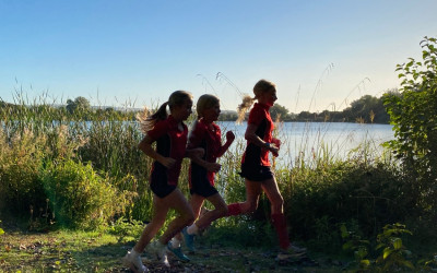 three girls running along the lake
