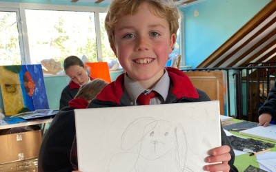 boy holding up drawing of his favourite teddy