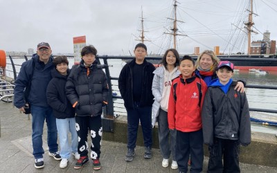 children and teacher in front of ship